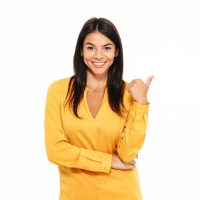 Portrait of a smiling attractive woman pointing finger away at copy space isolated over white background
